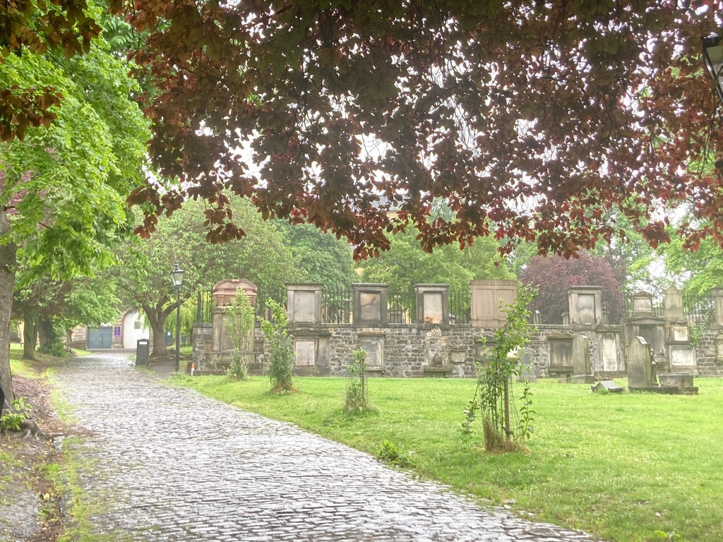 Een wandelpad in Blackfriars Kirkyard in Edinburgh, met graven en een groen gazon.